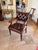 A hand carved library armchair, with an upholstered leather panel back and seat, with brass nail head trim, scroll arms,...