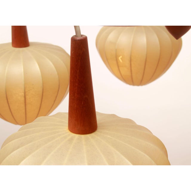 Elegant 1960s pendant lamp. with five identical cocoon shades. Shade diameter 20 cm. Teak wood construction. Fully...