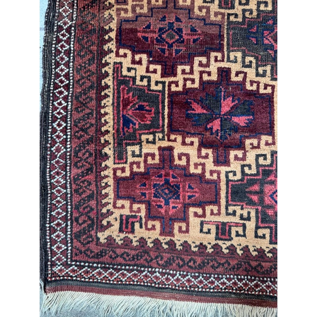 This striking vintage Balutch rug features a bold, geometric layout with repeating tribal star medallions in deep...