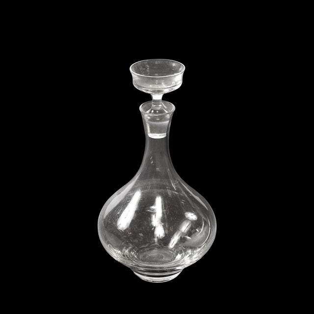 This Mid-Century Modernist sculptural crystal decanter, created circa 1960, showcases the clean lines and elegant...