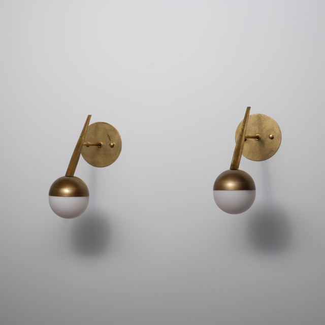 This pair of Italian wall sconces from the 1950s combines a refined modernist silhouette with rich brass surfaces and...