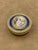 Circular 18K gold snuffbox with a painted scene depicting a young shepherdess seated in a bucolic landscape, with a white...