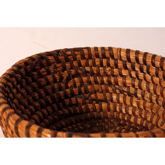 This antique woven basket embodies traditional craftsmanship and the timeless charm of vintage utilitarian objects. Its...