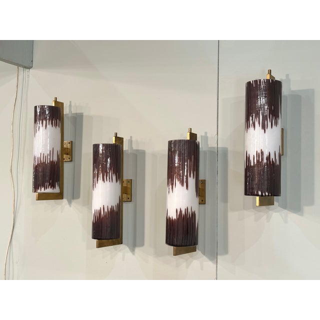 Four 1960s wall lamps by Ludovico Diaz De Santillana for Venini, with brass frames and glass diffusers. This piece is...