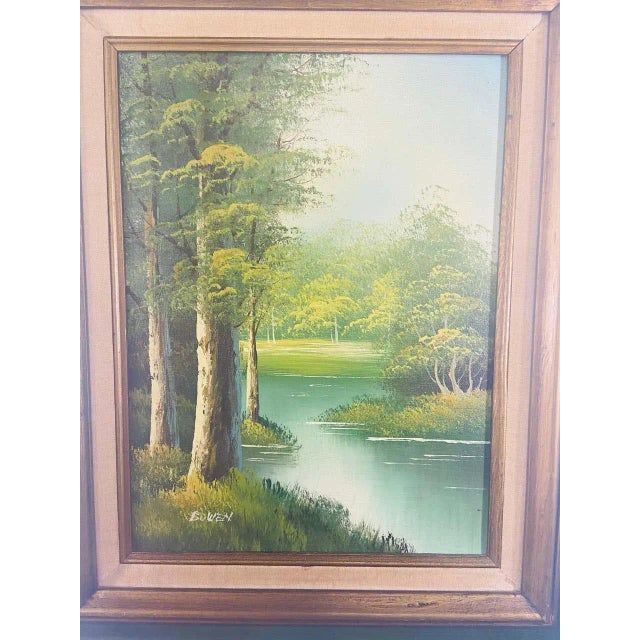 An oil on canvas landscape painting featuring a peaceful scene of a river in the middle of the wood. The painting is made...