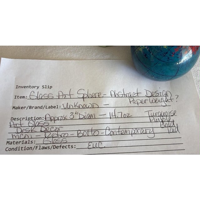 Handcrafted art glass paperweight features a celestial or planetary design with deep cobalt blue, teal, and earthy red and...