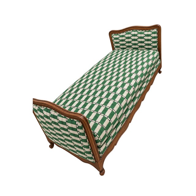 A sculptural carved wood daybed with beautifully shaped ends and a long, elegant silhouette. Green-and-ivory patterned...