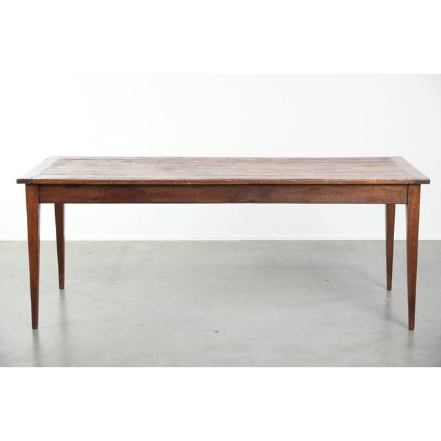 This charming antique French pine dining table features an oak base and is equipped with a practical drawer. This...