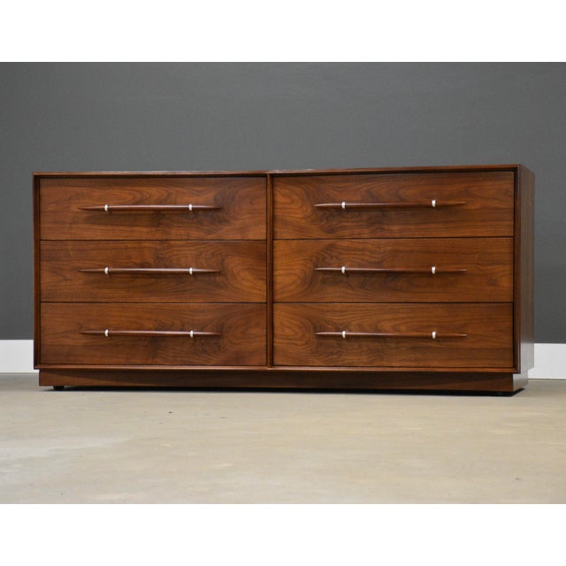 A rare mid century modern walnut six drawer dresser designed by T.H. Robsjohn Gibbings for Widdicomb with wooden and...