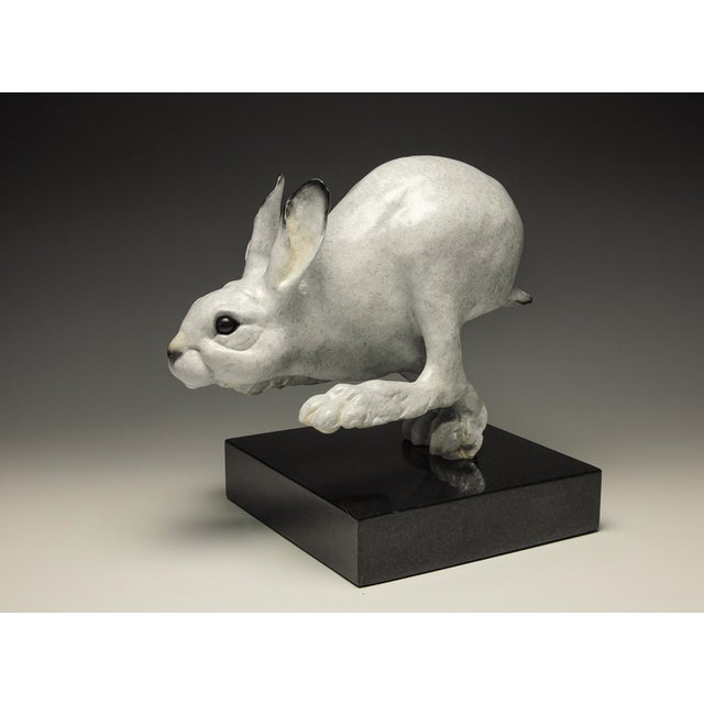 This bronze sculpture captures a dynamic moment of a hare in mid-leap, conveying a sense of energy and movement. The...