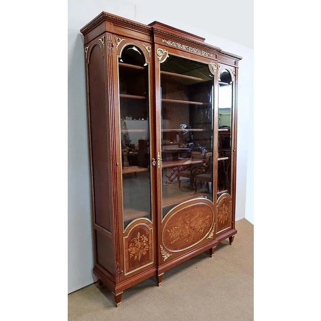 Large bookcase in solid mahogany and veneer, opening with three doors. These doors are composed, on three quarters of...