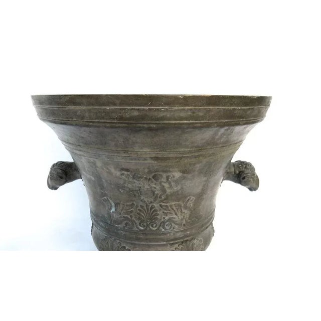 Large mortar patinated bronze. Bell shaped molded on foot, he has two side handles of ram's heads. The body is decorated...