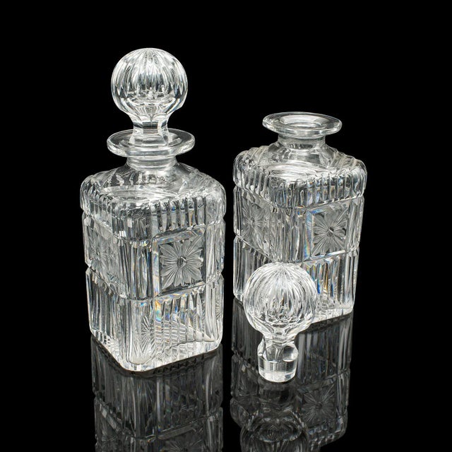 This is an antique decanter service. An English, crystal glass pair of spirit vessels upon a walnut plinth by Mappin &...