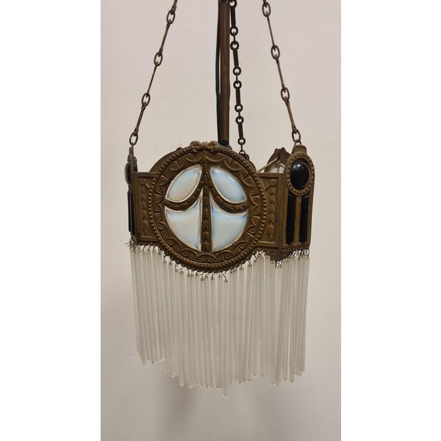 Refined art deco chandelier ' Triangular shape chandelier with golden bronze structure, lattimo and red glass plates with...