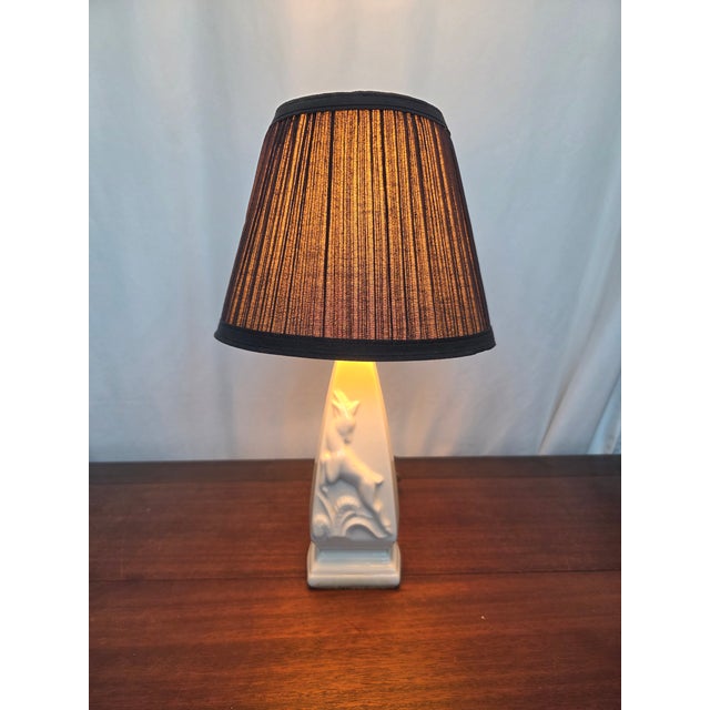 This elegant vintage boudoir lamp features a sculptural white ceramic base adorned with a graceful leaping gazelle motif,...