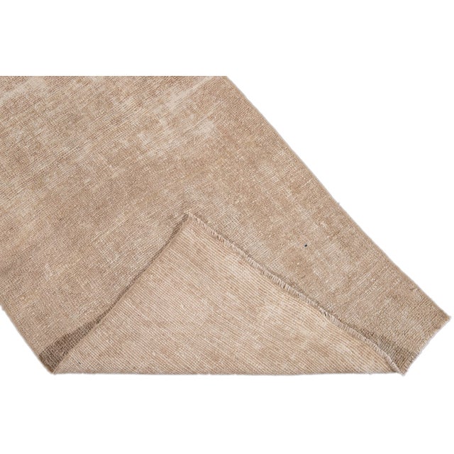 Beautiful vintage Turkish hand knotted wool rug with a Beige field. This rug has accents of ivory and gray in a gorgeous...