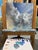 This oil painting captures a dynamic sky filled with swirling clouds, blending hues of blue, gray, and soft white. The...