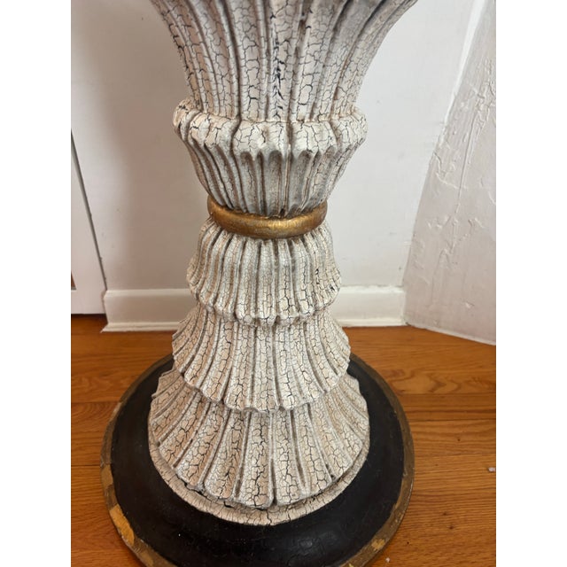 carved wooden fluted hourglass table. dark circular base with gold accents.