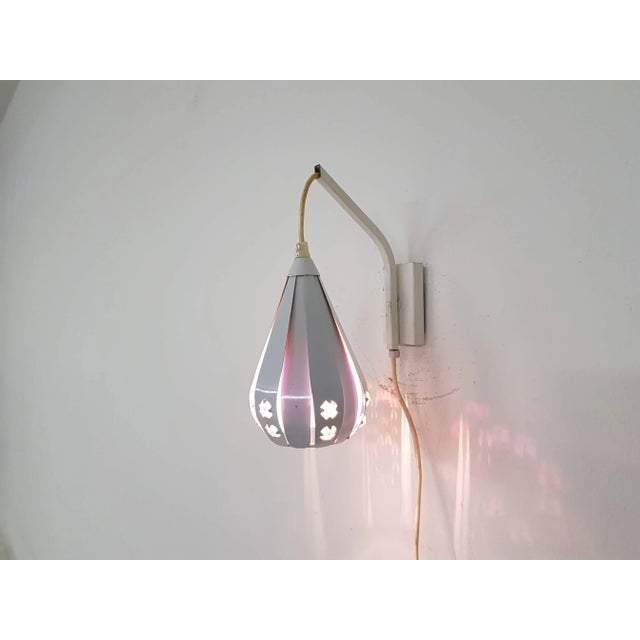 White wall lamp by Werner Schou. This white metal lamp has a purple inside and diamond shaped details. Up to 250V...