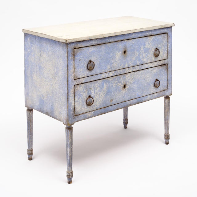 Italian chest with striking hand-painted design in cream and blue tones, supported by four fluted and tapered legs. The...
