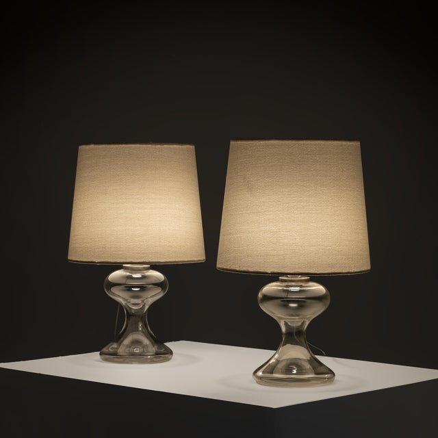 A pair of sculptural table lamps attributed to Ingo Maurer, executed in hand-blown clear glass and fitted with bespoke...