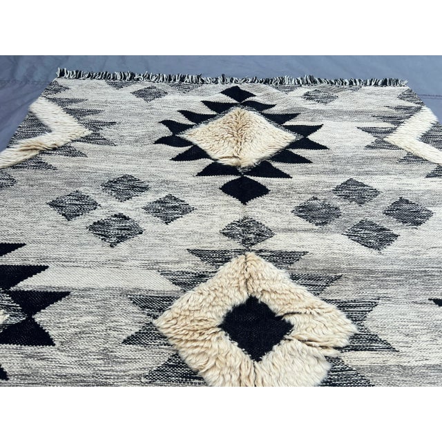 This vintage Afghan Sumak Kilim rug showcases a striking black and cream geometric pattern with a bold tribal design,...