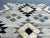 This vintage Afghan Sumak Kilim rug showcases a striking black and cream geometric pattern with a bold tribal design,...
