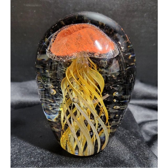 Striking Murano-style blown art glass paperweight featuring a vibrant jellyfish design in rich orange, yellow, and black...