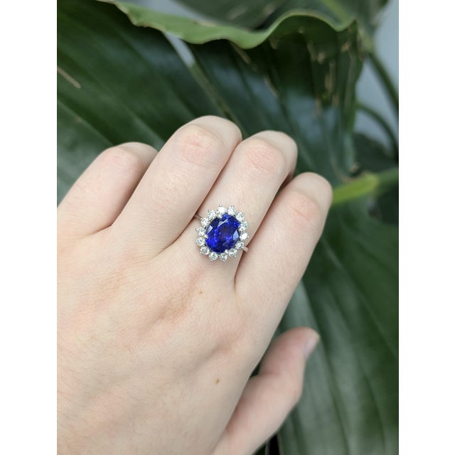 This elegant tanzanite ring showcases a 4.39-carat oval-shaped center stone (10x8mm) with striking deep blue-violet hues....