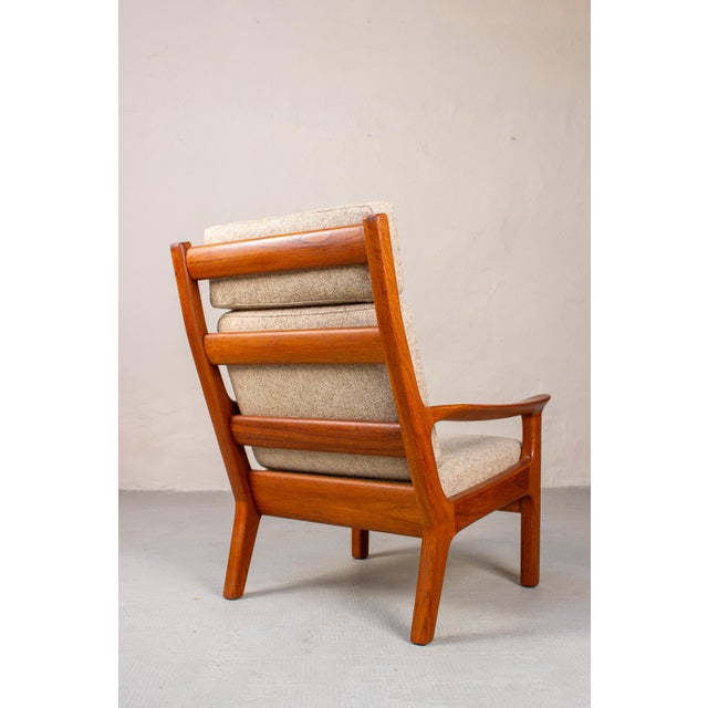 This high-backed armchair by Juul Kristensen is an inviting chair for reading and relaxing. The warm color of the teak...