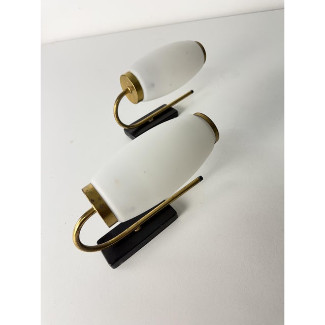 Set of two opaline glass and brass wall lamps in the Stilnovo style, 1950s Intact and in good condition, E14 lamps. They...