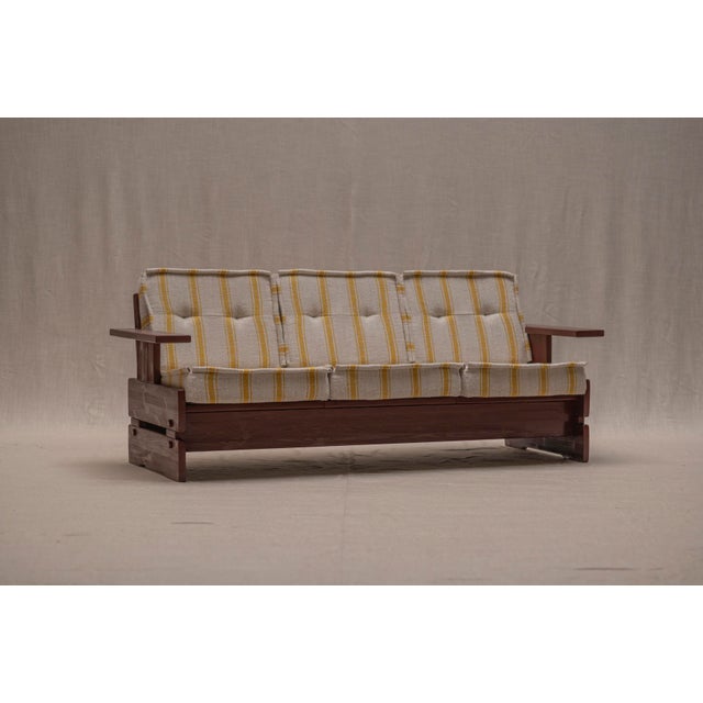 Characterful three-seater sofa from the 1970s, featuring a substantial solid wood frame with bold geometric lines and...