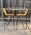 Striking pair of mid-century modern bar stools featuring sculptural black-finished wrought iron frames with distinctive...