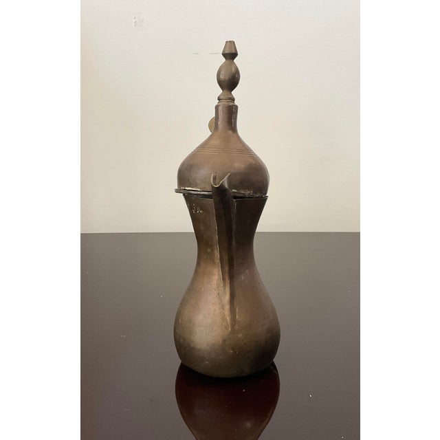 This beautifully crafted dallah, often used for brewing and serving coffee, made of brass, features intricate designs...