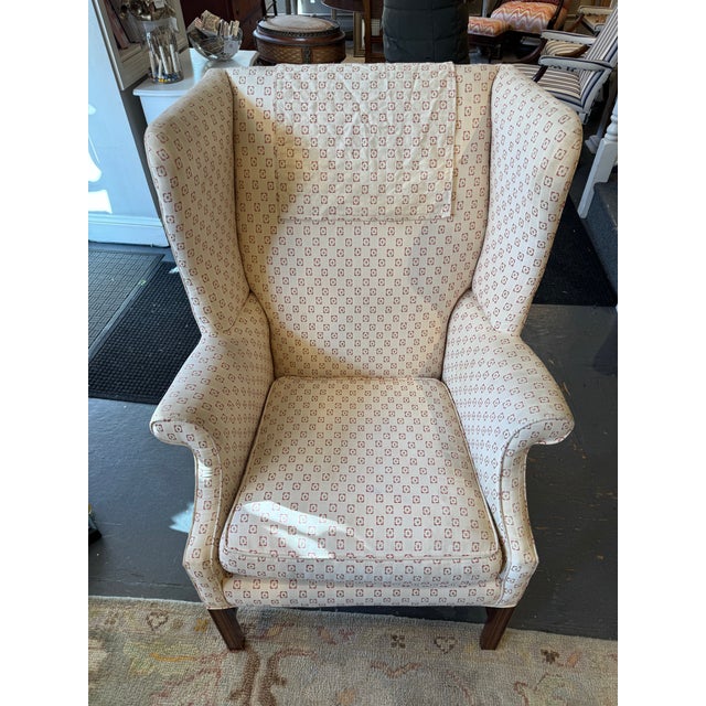 This is a vintage wingback chair. It has a mahogany Chippendale style base. It has a cream colored fabric with a geometric...