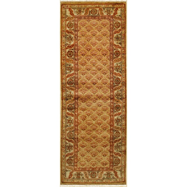 A hand-knotted wool rug, made in India and measuring 3' x 12'. Floral drawing carried across the field inside a...