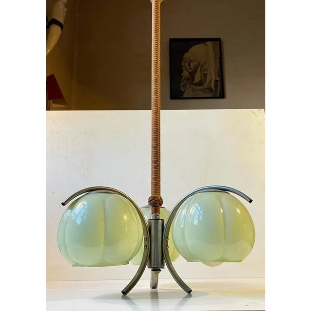 A stylish 3-shaded chandelier featuring 3 light green gourd shades, a nickel plated frame, hand-weaved/rolled rod with...