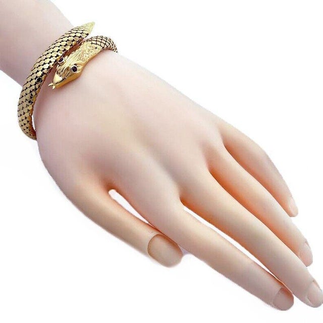 This beautiful bracelet is crafted from 18k yellow gold featuring a bypass style snake with ruby eyes polished had and...