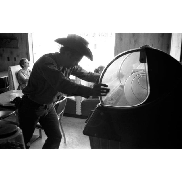 James Dean During The Filming of "Giant" MARFA, TX - July 1955: Actor James Dean picks a song on a juke box in a bar...