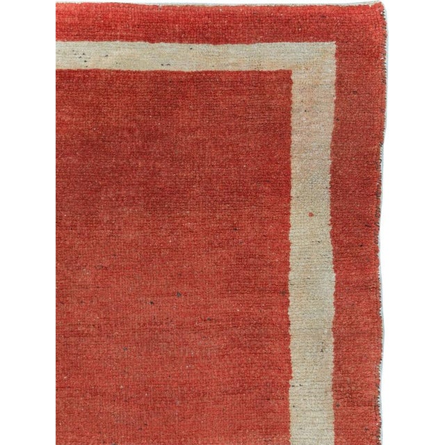A vintage Turkish Oushak carpet from the second quarter of the 20th century featuring a minimalistic solid orange ground...
