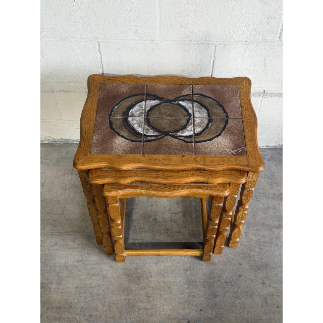 A set of three space-saving nesting tables styled with curved aprons and turned support legs. Each surface features inset...