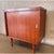 Vintage Mid-Century Modern cabinet , featuring warm wood grain, clean architectural lines, tapered legs, and sleek...