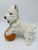 A vintage chalkware terrier dog figurine posed playfully with its front paws resting on a ball. The white dog has hand-...