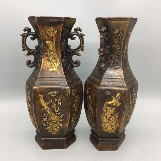 A striking pair of Chinese hexagonal bronze vases featuring extensive gold (gilt) detailing. Each vase has a faceted,...