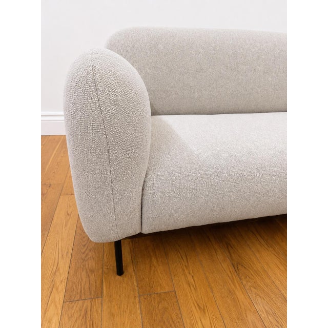 Mid century inspired sofa in a cool toned beige boucle. Black metal legs add to its clean contemporary look.