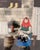 Signed Russian folk art print featuring a woman wearing a red babushka, holding a cat in her lap. The print is dated 2003....