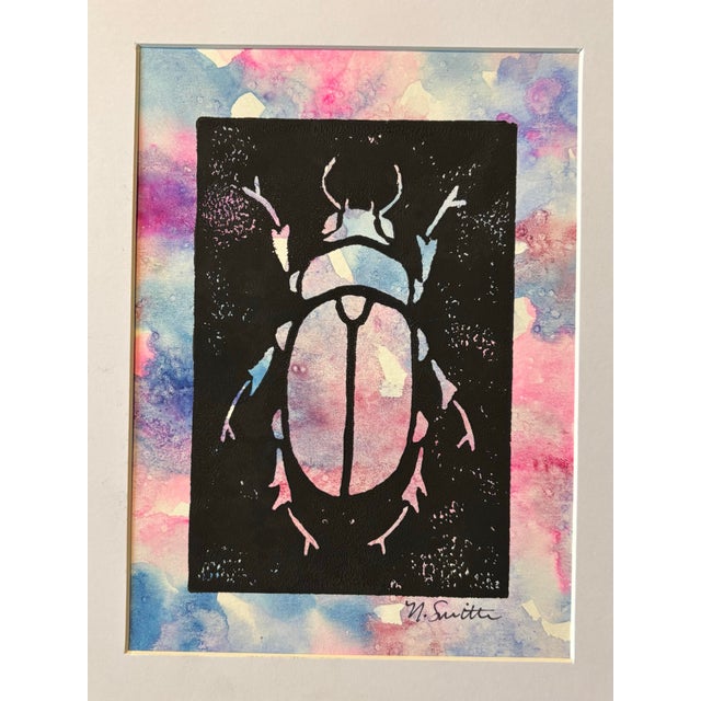 An original hand-carved block linocut featuring a detailed beetle motif, individually printed with black ink and finished...