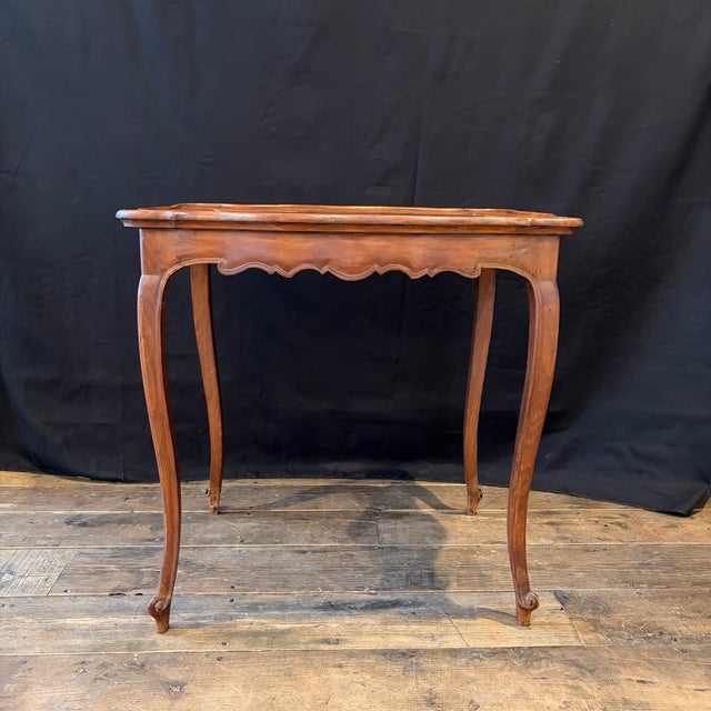 Elegant French Louis XV walnut side table or petite desk with a graceful serpentine silhouette and delicate cabriole legs...
