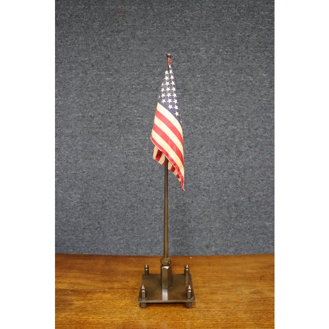Antique American table flag displayed on a substantial brass stand. The square stepped base has four decorative corner...
