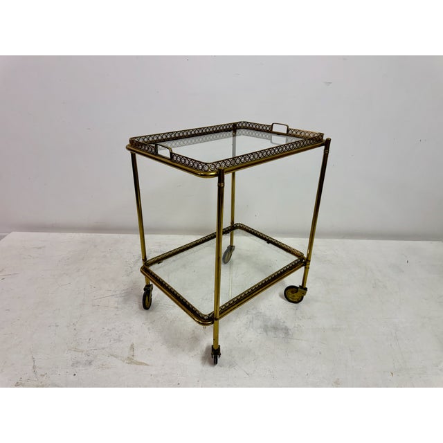 A stylish French brass drinks trolley dating from the 1960s, featuring two removable glass trays framed by finely pierced...